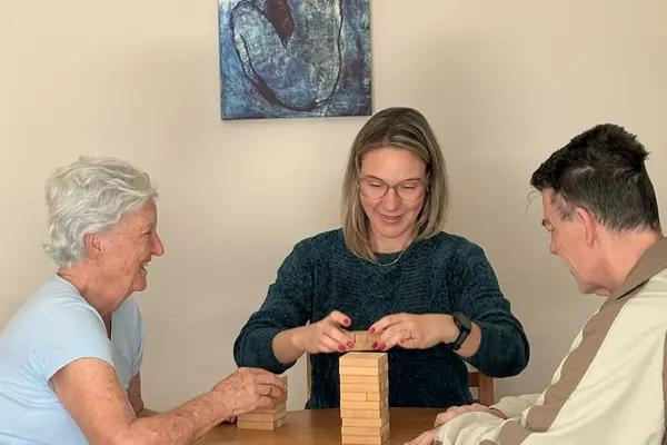 Idosos e profissional participando de atividade com blocos de madeira em detalhe