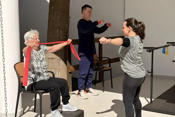 Idosa fazendo exercício de fortalecimento com faixa elástica durante a rotina