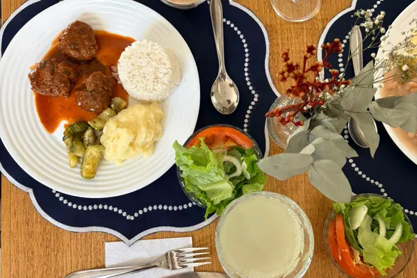 Refeição com arroz, carne, purê, legumes e salada servida em mesa posta